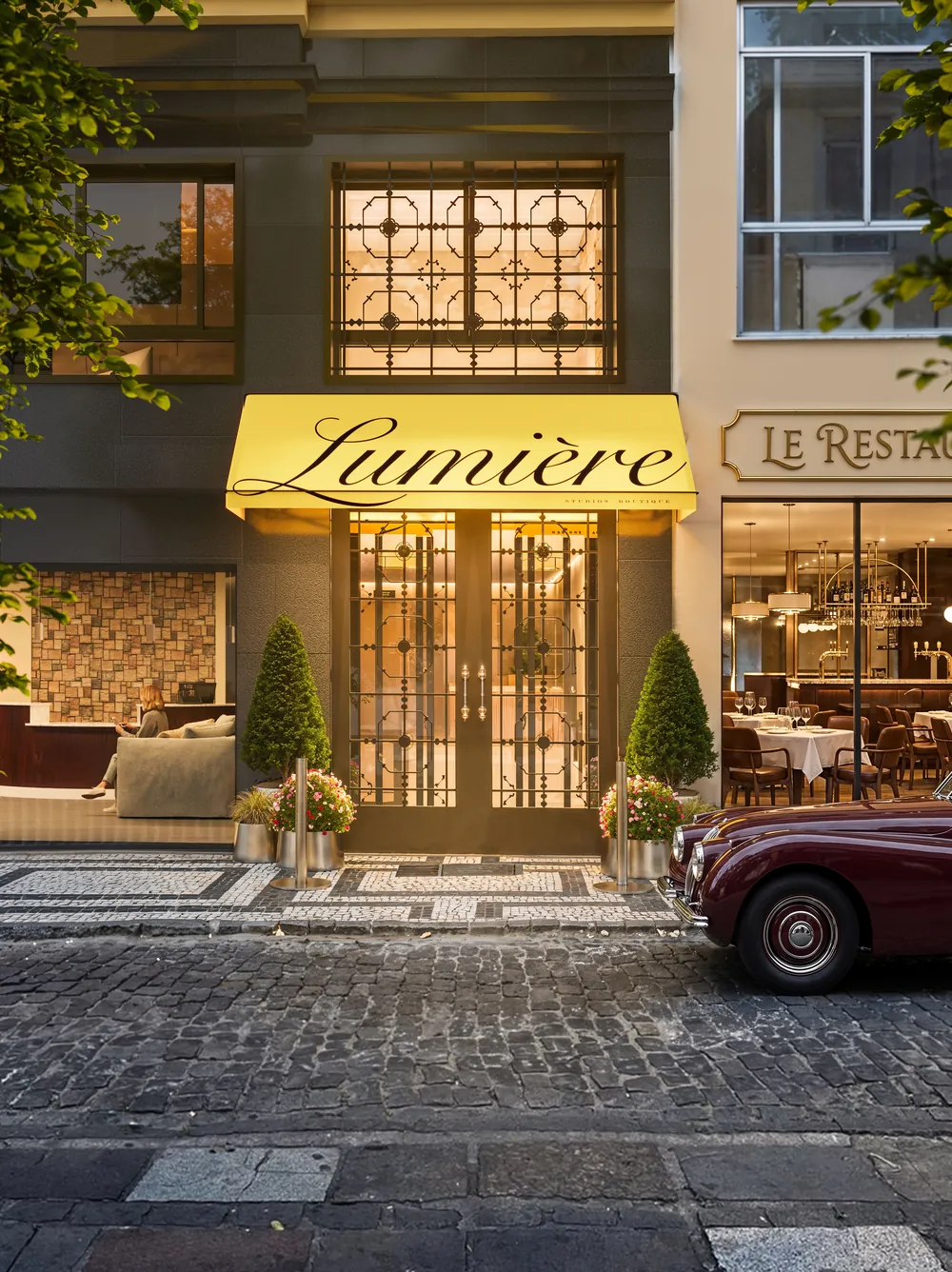 Acesso do Lumière com toldo amarelo e portão de ferro trabalhado